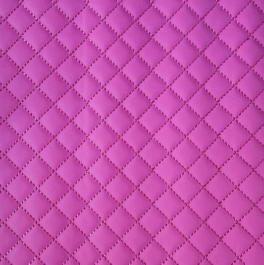 A close-up of a quilted fabric texture in a vibrant magenta pink, showing a repeating diamond pattern stitched together.