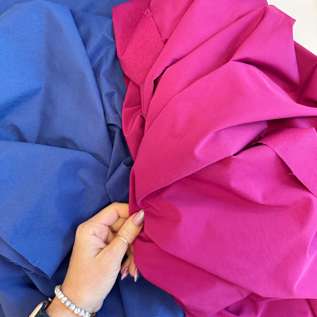 Hand holding pink fabric next to blue fabric