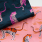 Two folded pieces of Ruby Star Society's Poolside Too Rayon fabric featuring a tiger print pattern. The top fabric is dark teal with pink and lavender tigers, and the bottom fabric is a sorbet pink with orange and white tigers swimming in water.