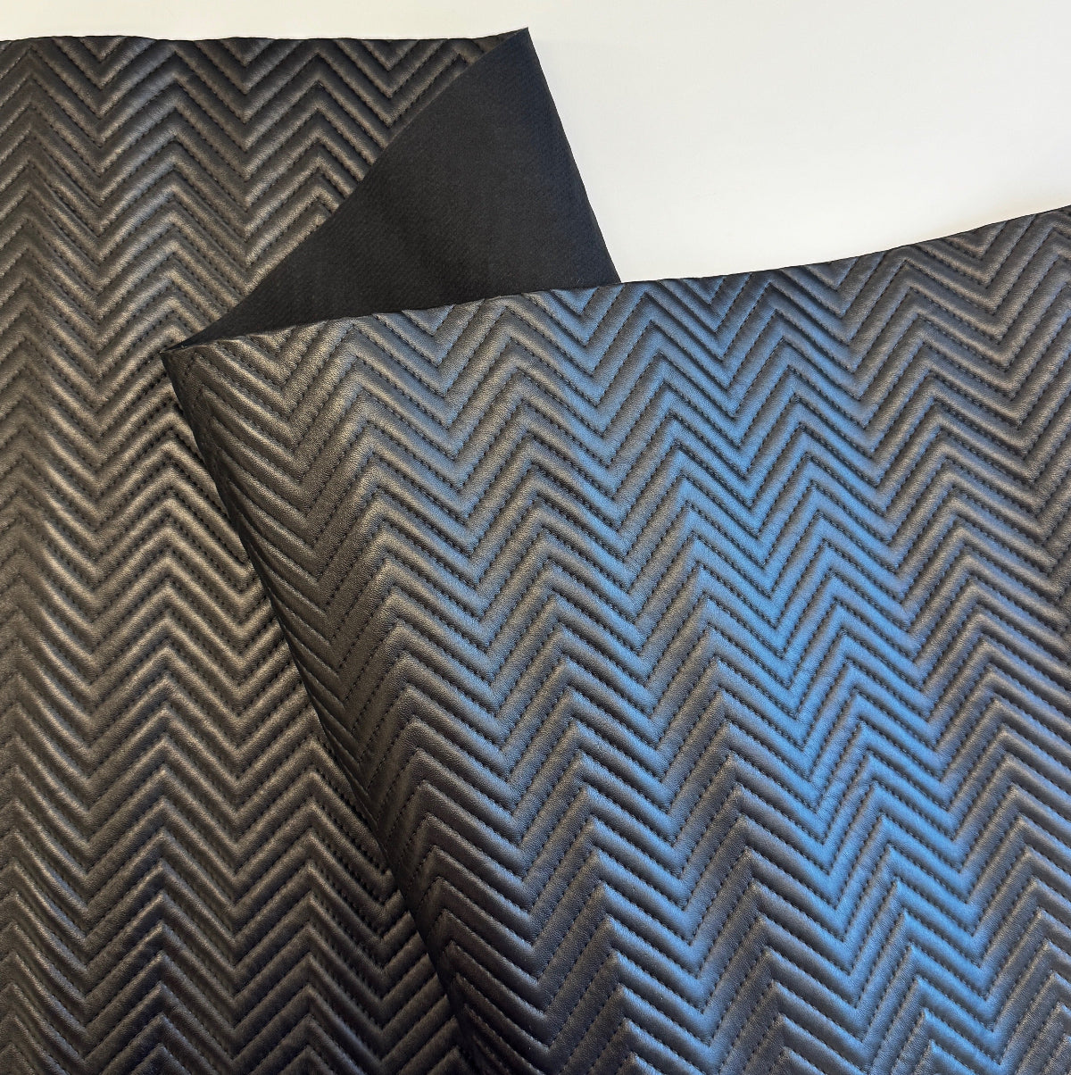 Textured fabric with a herringbone pattern in black and blue on a white background
