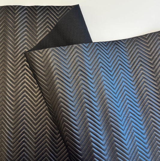 Textured fabric with a herringbone pattern in black and blue on a white background