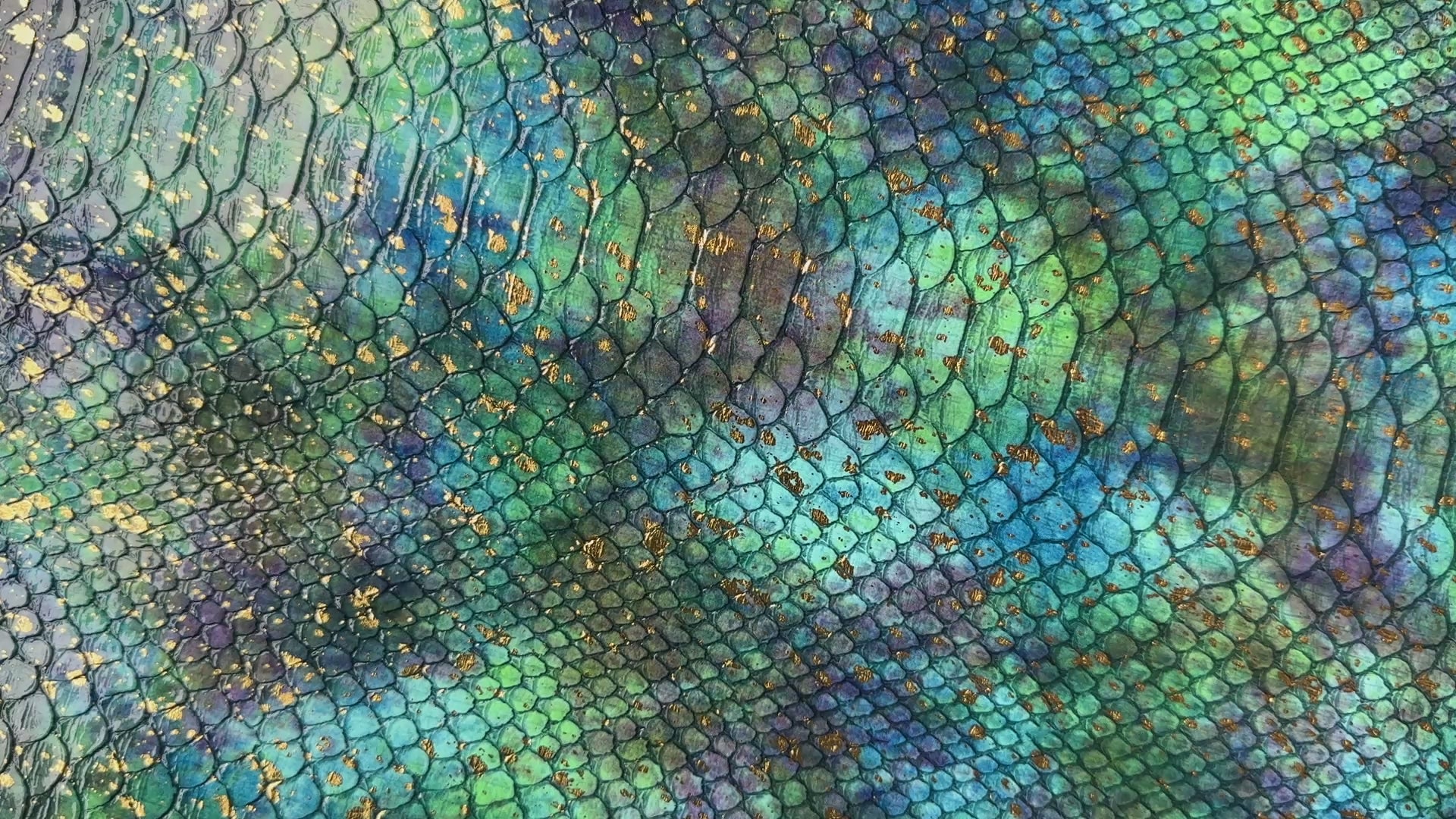 Close-up video of teal and blue embossed serpent vinyl with a scale texture and gold foil accents. 