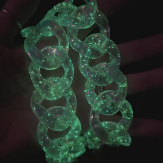 A video of a glow-in-the-dark neon green acrylic chunky chain strap held in hand.
