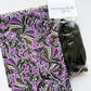 Sew Hungry Hippie bag-making supplies featuring vibrant purple cotton fabric with an abstract swirling pattern in dark olive green, white, and black, paired with dark olive green continuous zipper chain and matching metal zipper sliders. Coordinating fabric and zipper supplies for handmade handbags, zipper pouches, cosmetic bags, and DIY sewing projects.