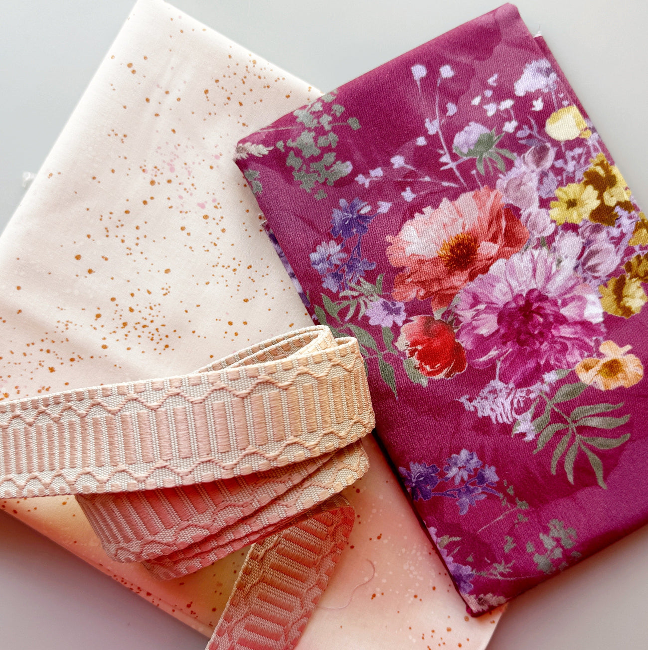 Purple floral fabric with coordinating speckled fabric and cream webbing for bag making