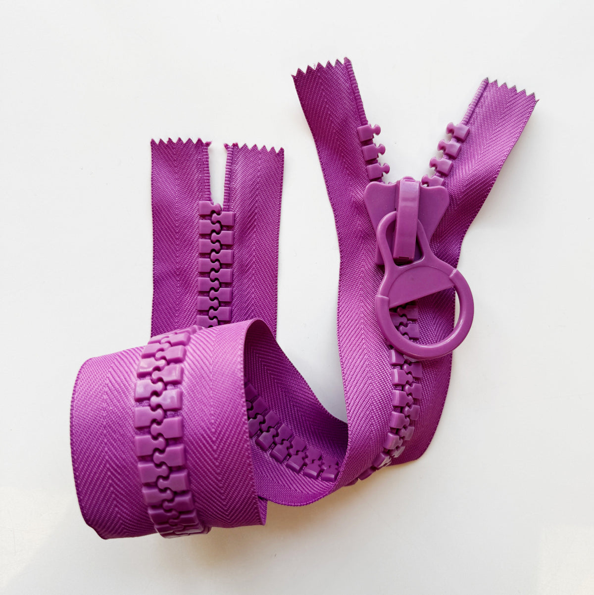 Purple molded plastic zipper with chunky teeth, matching circular ring pull, and textured herringbone zipper tape