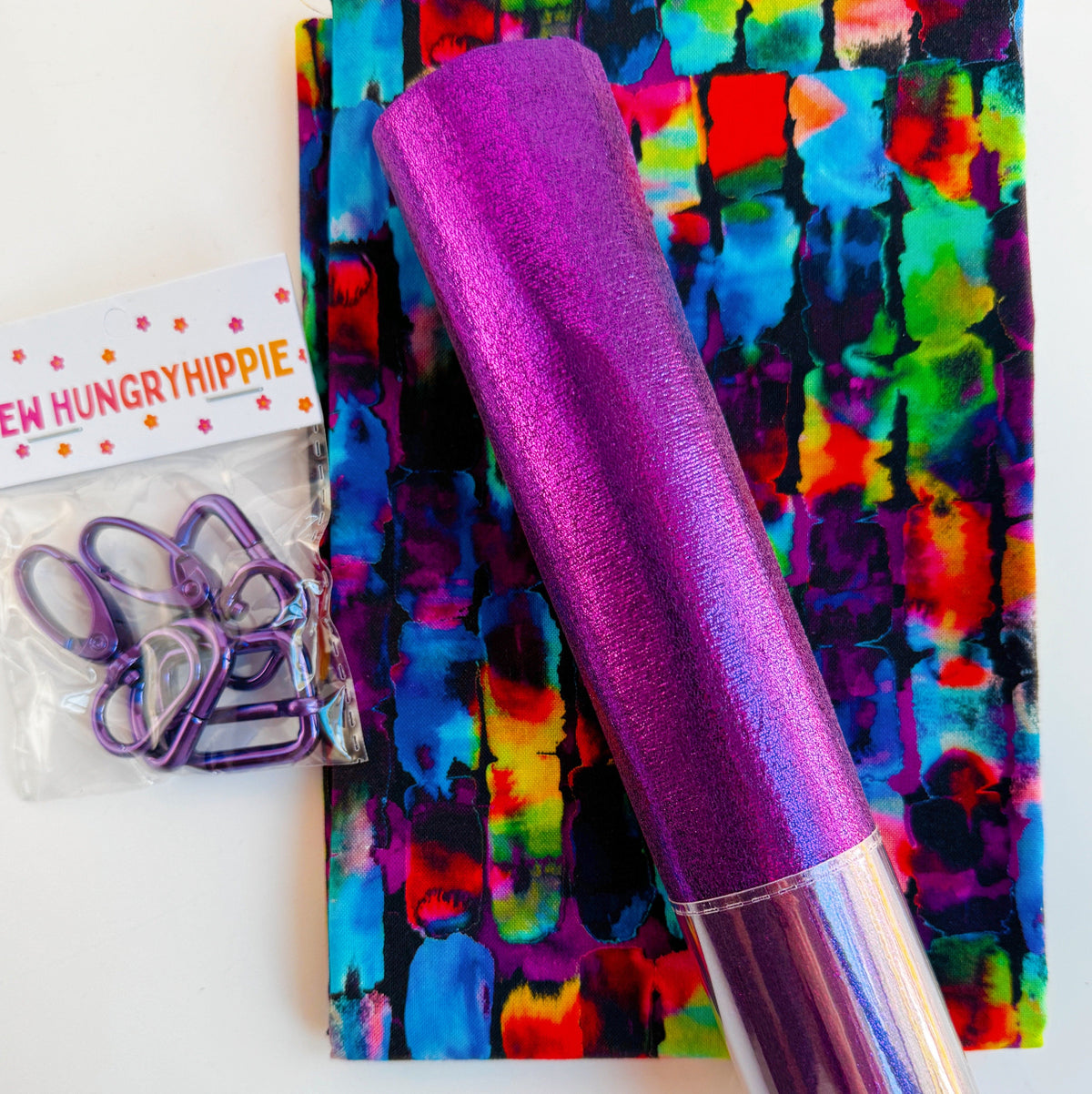 Purple soft metallic vinyl, colorful printed fabric, and purple bag hardware for sewing projects