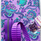 Purple paisley fabric with coordinating purple webbing, zipper tape, and metal bag hardware for a sewing project.