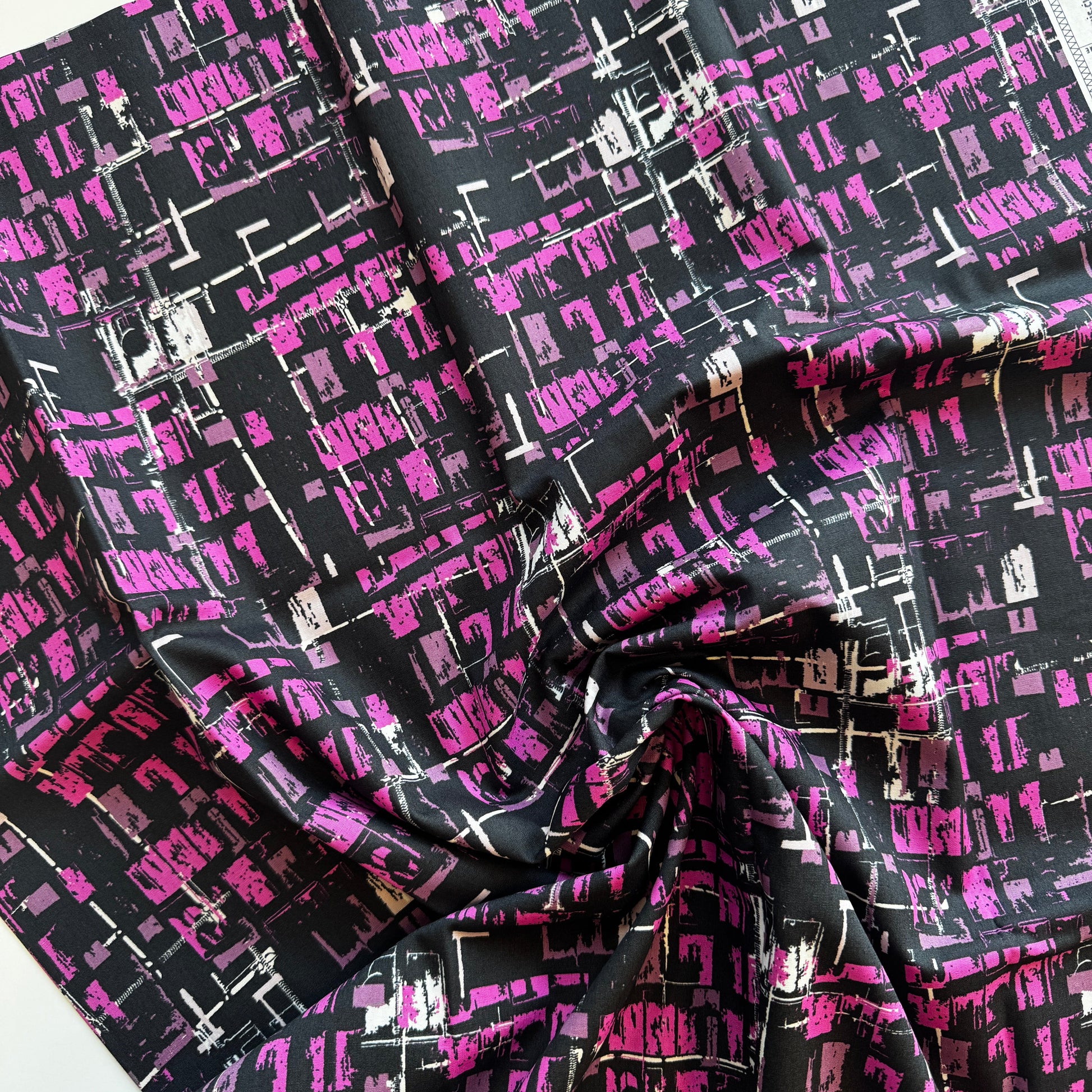 Fabric with a black and pink geometric pattern on a white background