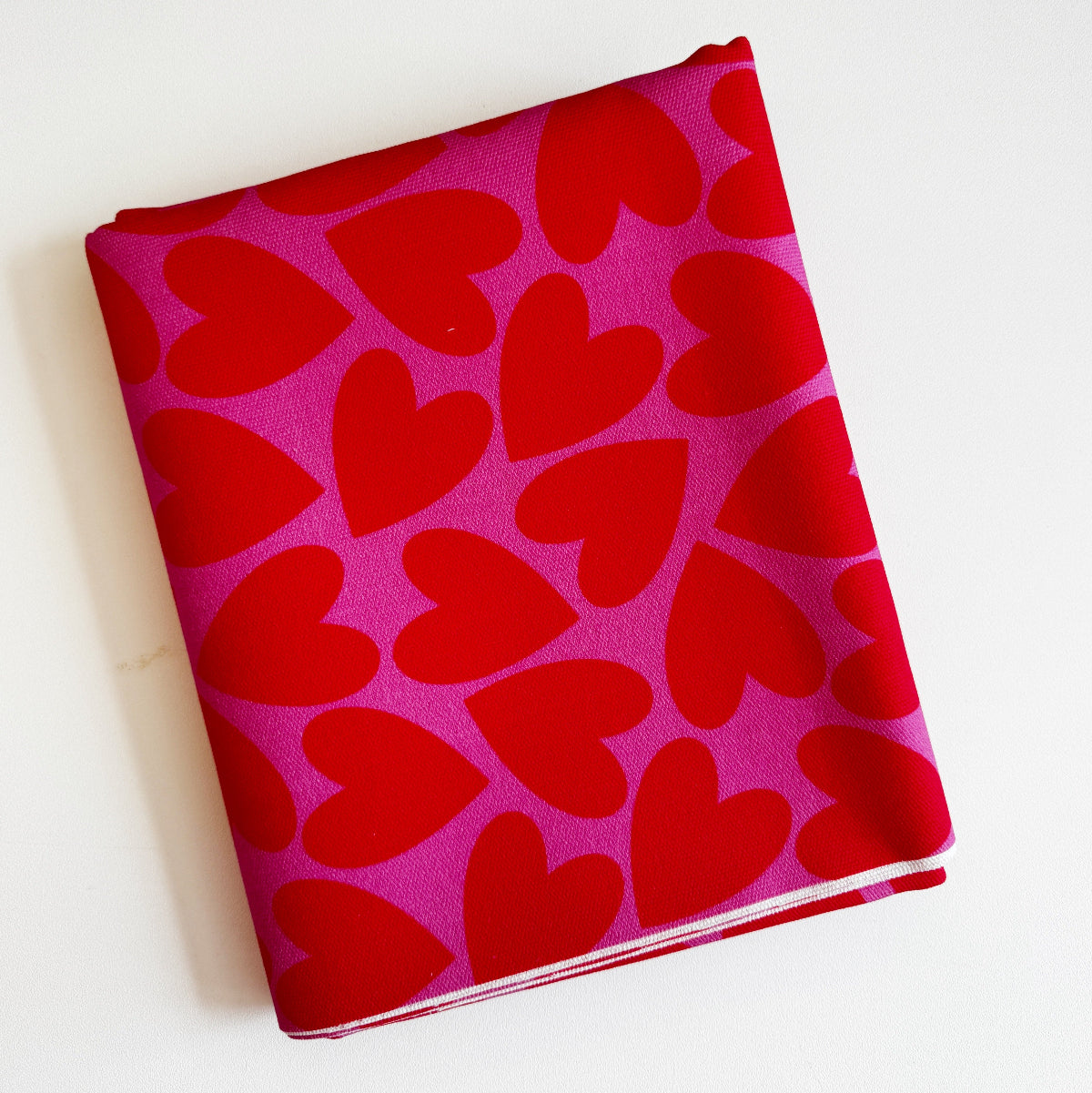 Folded fabric with red heart pattern on a pink background