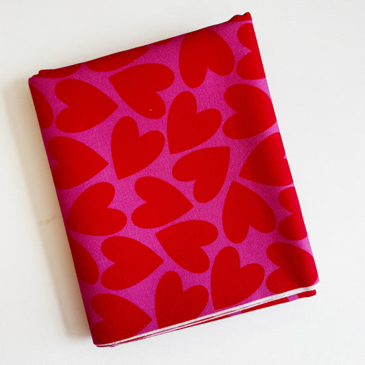 Folded fabric with red heart pattern on a pink background