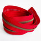 Red zipper with bronze teeth on a white background