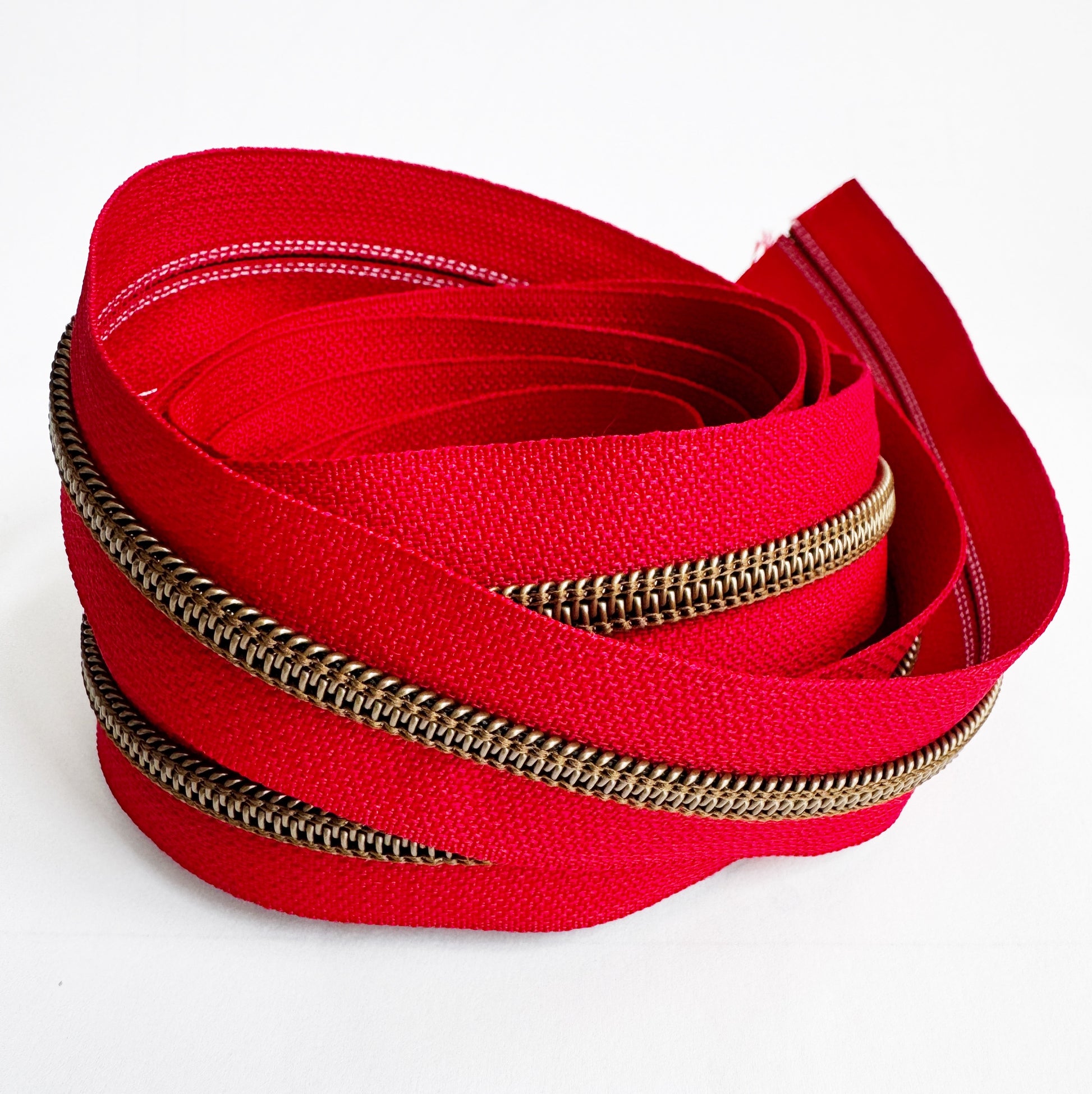 Red zipper with bronze teeth on a white background