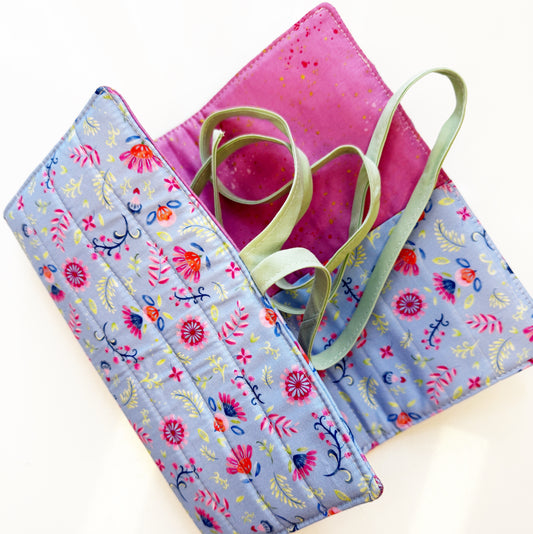 Floral-patterned fabric roll with pink cover and green ribbon on a white background