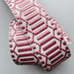 A close-up of a woven elastic strap with a geometric pattern in dusty pink and white, shown on a neutral light gray background.