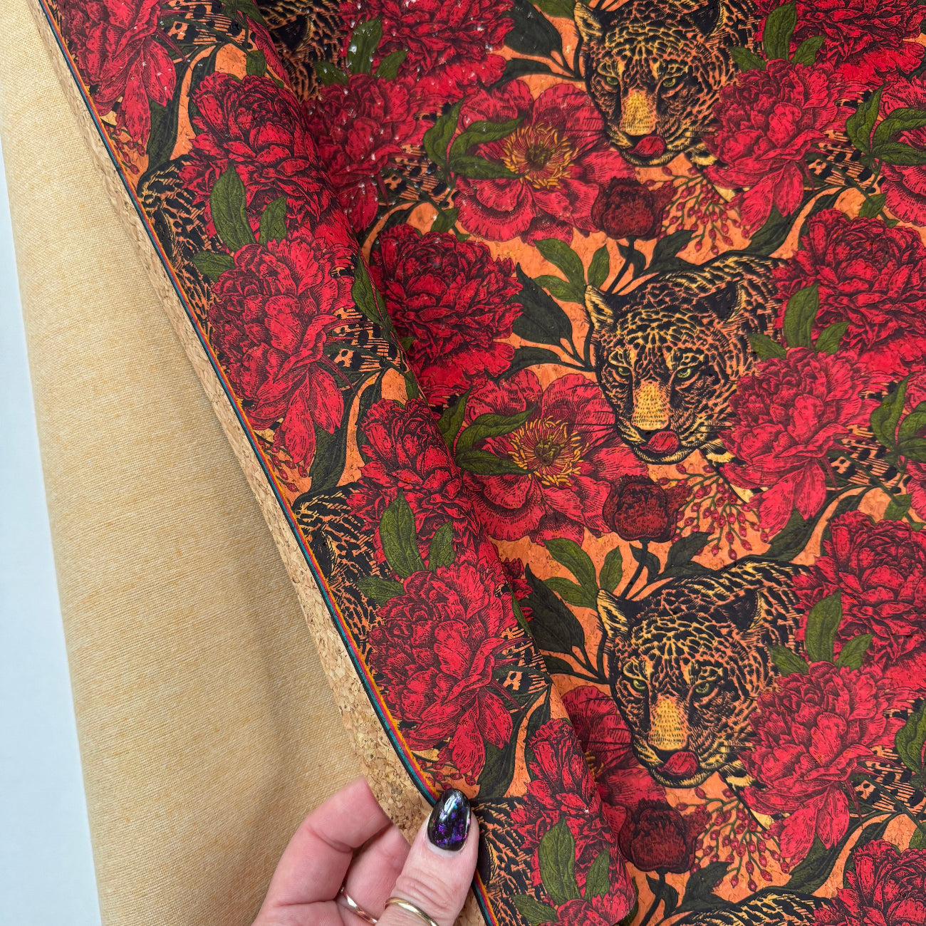 Person holding a rolled-up piece of fabric with a floral and bird pattern.