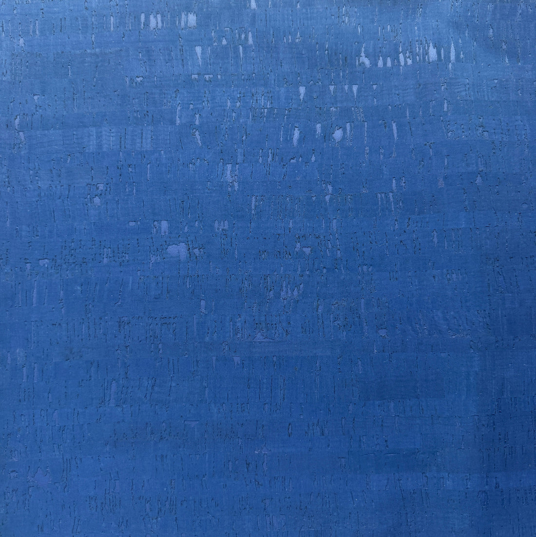 A close-up of a textured blue cork surface with subtle horizontal brushstrokes and slight tonal variation.