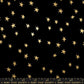 A flat lay photograph of a black fabric pattern featuring scattered, hand-drawn metallic gold stars of varying sizes. A quilting ruler at the bottom edge marks measurements in inches from 1 to 7, displaying the text "RUBY STAR SOCIETY" printed repeatedly in gold.