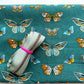Sage green zipper tape on dark teal fabric with colorful illustrated butterfly print for bag making