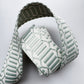 A light sage green and white woven fabric belt with a geometric pattern, folded and displayed on a light gray background.