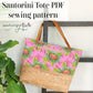 Santorini tote bag with pink floral pattern and woven base, hanging on a rack with 'sewhungryhippie' branding.