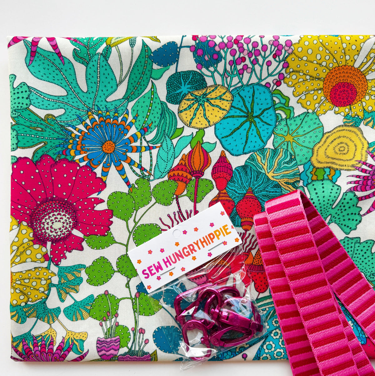 Sew Hungry Hippie floral fabric with pink ribbed webbing and dark pink metal swivel hooks for bag making