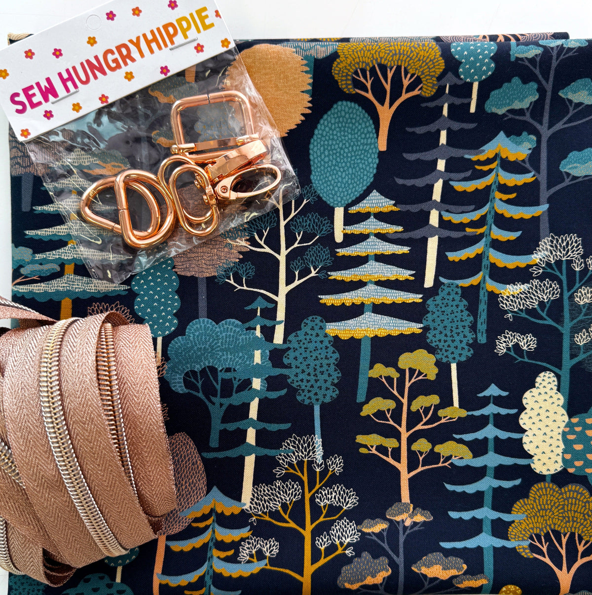 Sew Hungry Hippie navy forest print fabric with rose gold bag hardware and matching coil zipper tape