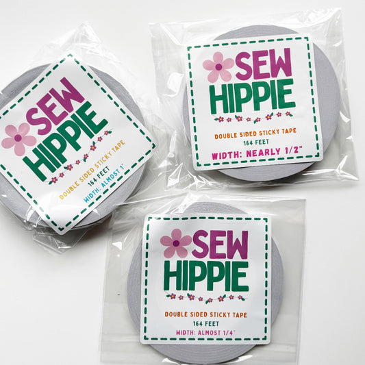 Three rolls of double-sided sticky tape in clear plastic packaging, each with a white label reading 'SEW HIPPIE' in pink and green text, arranged on a white background.