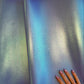 Gradient fabric swatch transitioning from blue to green with a hand for scale on a beige background