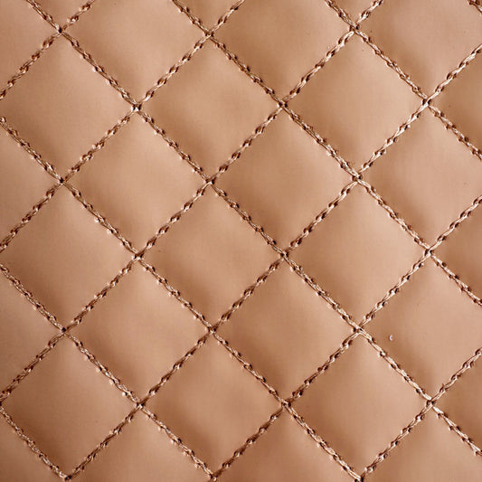 a detailed close-up of beige-colored vinyl with a quilted diamond stitch pattern, highlighting the texture and thread detail of the stitching.