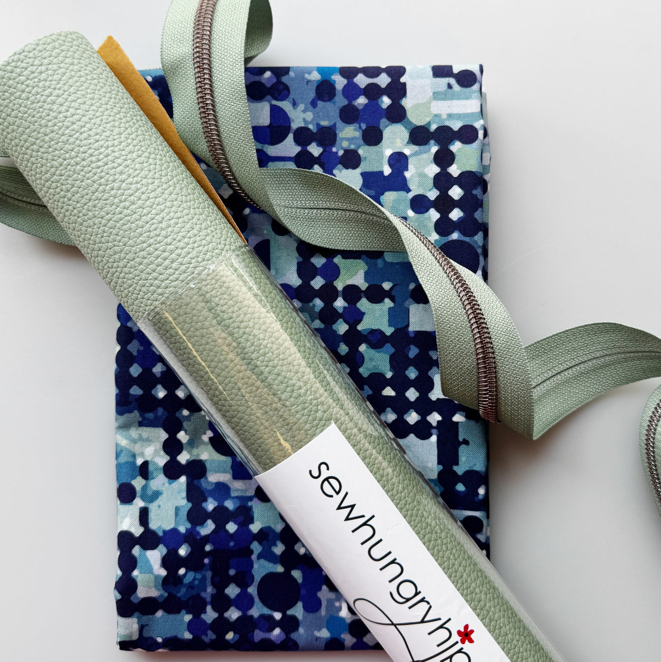 Blue geometric patterned fabric with mint green textured faux leather, webbing and zipper from Sew Hungry Hippie