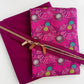 A detailed view of a SewHungryHippie bundle displaying folded magenta nylon and pink floral fabric secured with a zipper featuring three pulls.