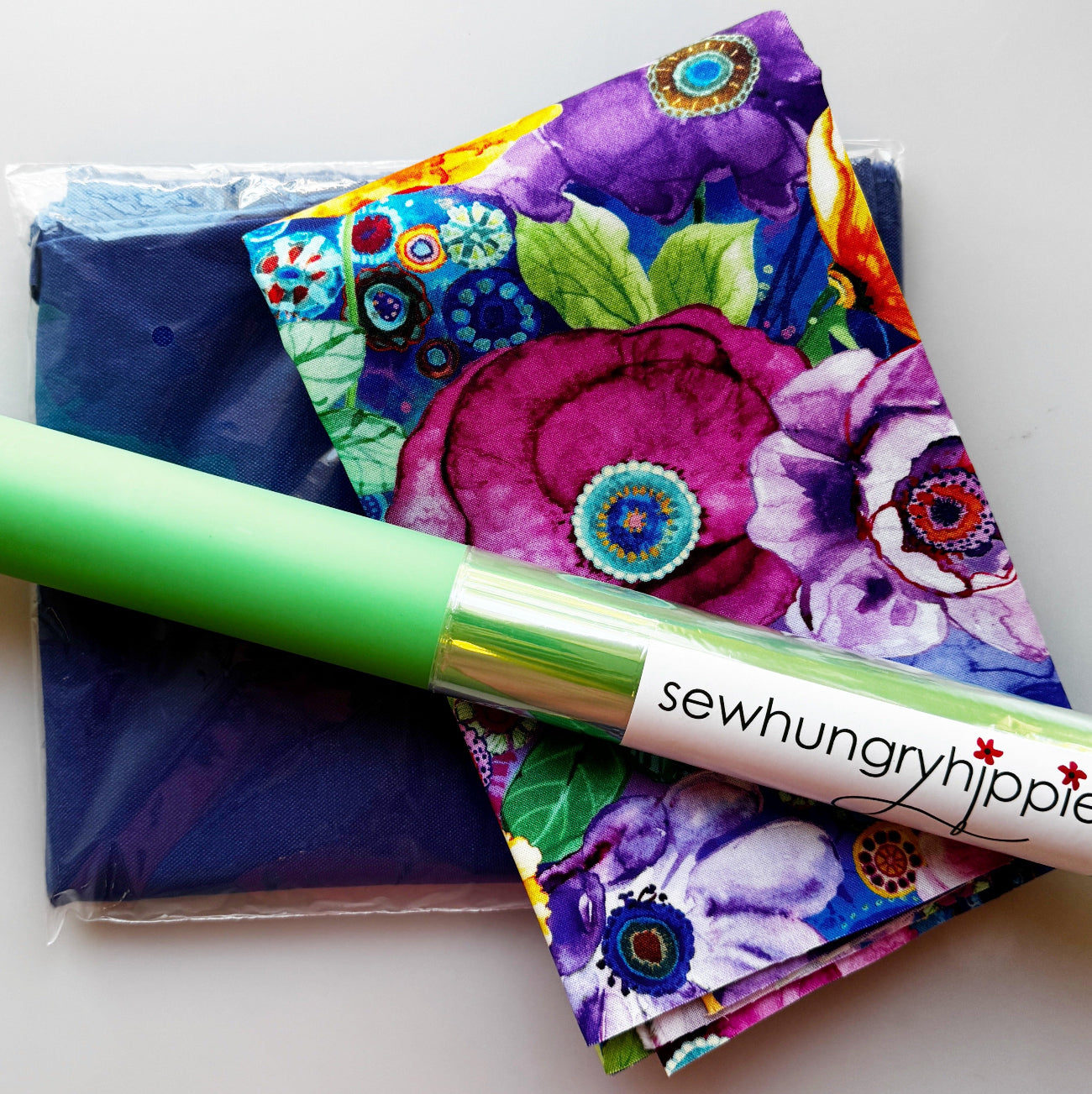 Sew Hungry Hippie colorful floral fabric bundle with navy sewing fabric and green sewing tool.