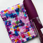 Colorful watercolor-style paint stroke fabric paired with dark purple textured faux leather from Sew Hungry Hippie