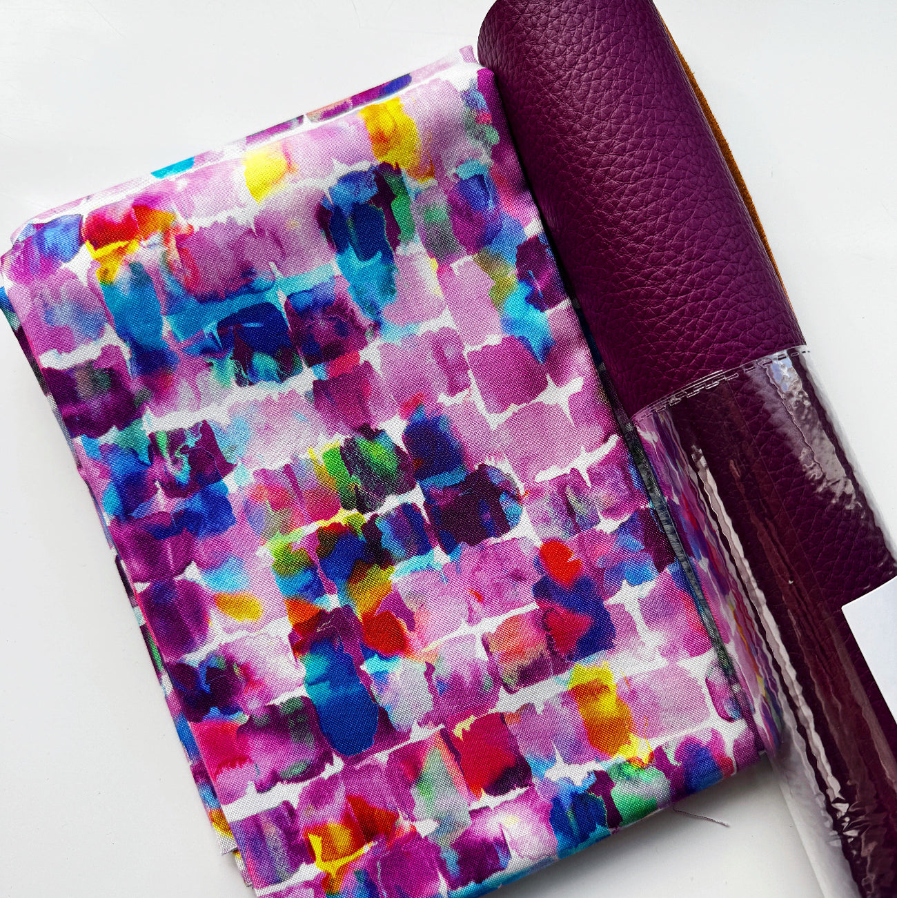 Colorful watercolor-style paint stroke fabric paired with dark purple textured faux leather from Sew Hungry Hippie