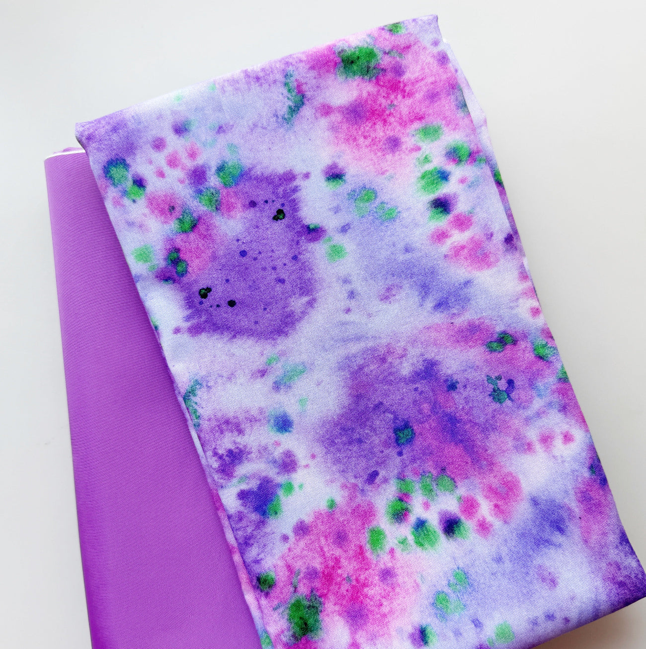 Purple, pink and green watercolor-style patterned fabric with a coordinating purple fabric from Sew Hungry Hippie