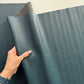 Hand holding a large sheet of blue leather-like material