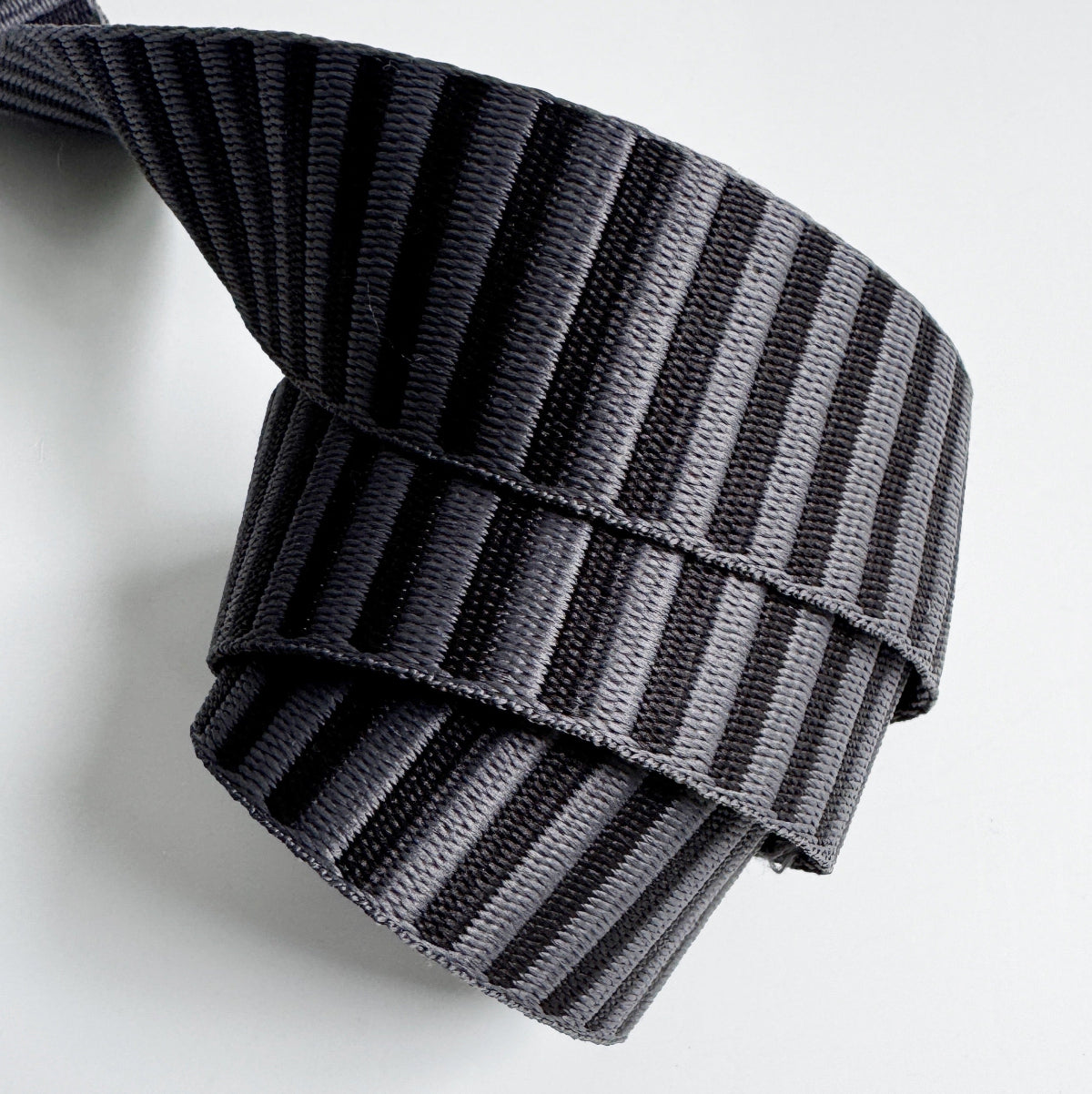 A 1.5-inch wide jacquard woven webbing strap featuring a charcoal grey and black horizontal stripe pattern, neatly coiled against a white background.