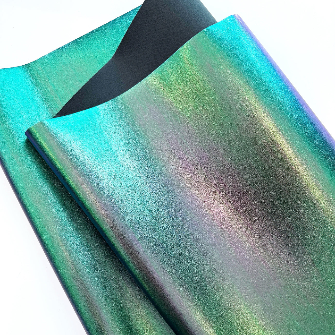 Close-up of iridescent green faux leather fabric showing color shift from teal to purple with a dark felt backing