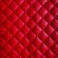 A close-up of bright red quilted leather texture with a repeating diamond pattern and pebbled grain.
