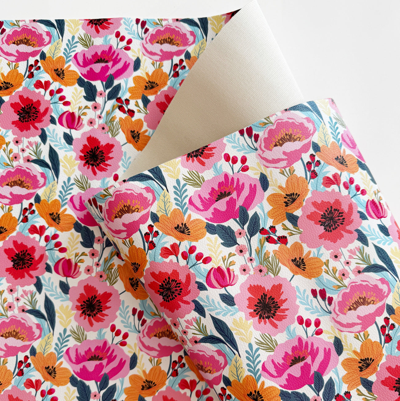 Closed up image of Poppy Punch floral vinyl fabric featuring vibrant pink, orange, and red flowers with detailed botanical pattern on a white background