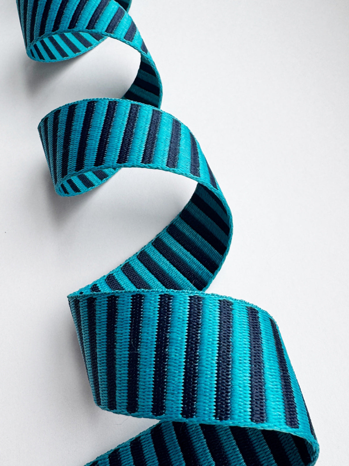 Teal and black striped webbing on a white background