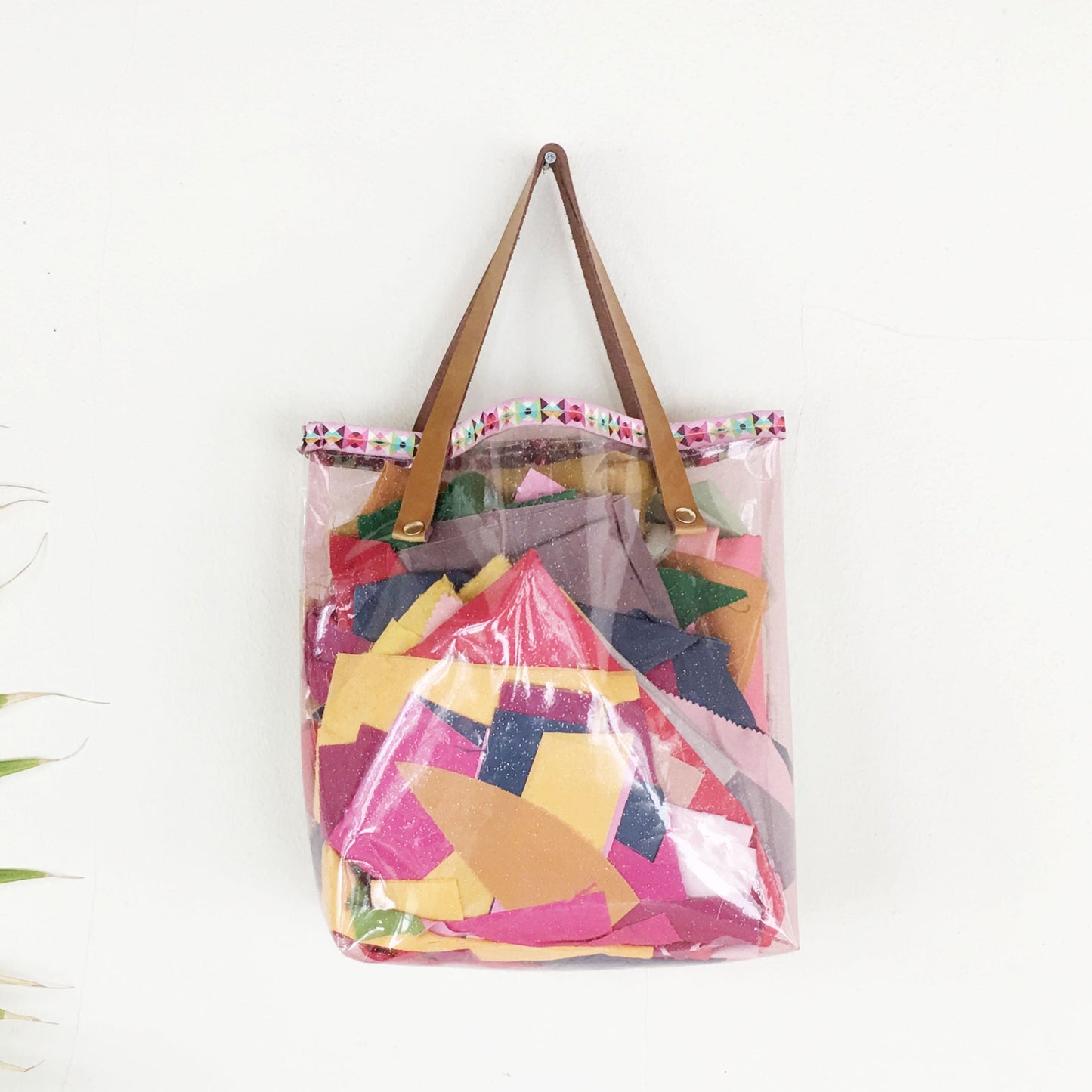 Transparent tote bag with colorful geometric pattern on a white background with palm leaf