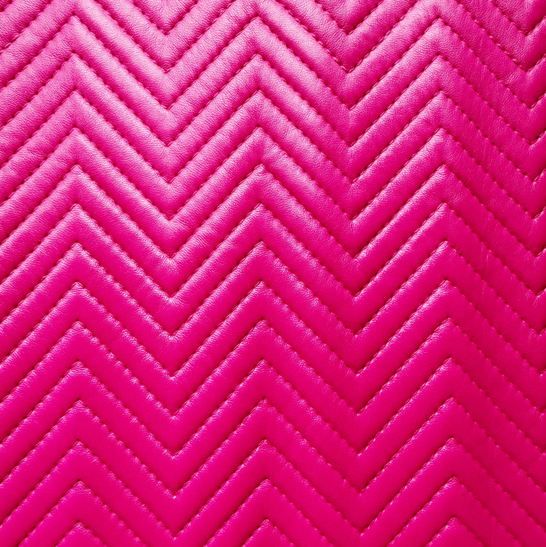Bright pink chevron quilted fabric texture with stitched zigzag pattern.