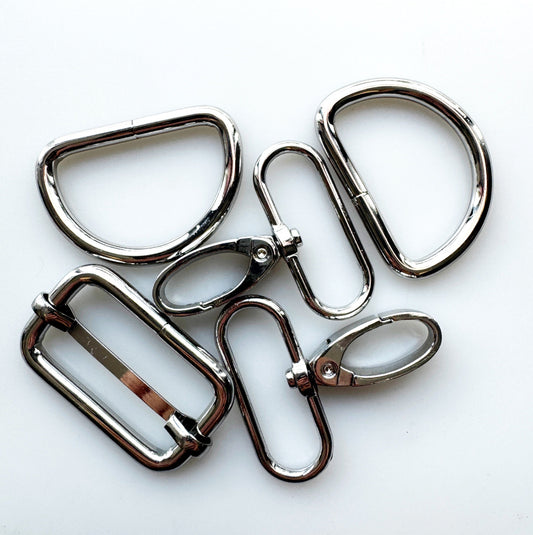 Six polished silver metal hardware components, including rings, loops, and clips, arranged on a plain white background.