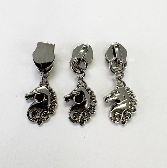 Three silver-toned unicorn-shaped zipper pulls with shield-shaped posts, arranged side by side on a plain white background.