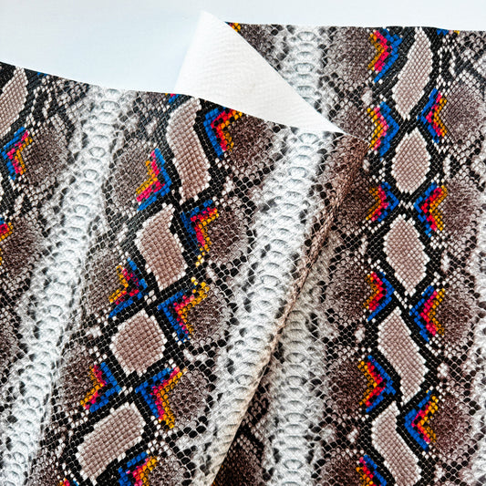 Close-up of faux snakeskin leather fabric with a grey python pattern and colorful neon geometric accents.
