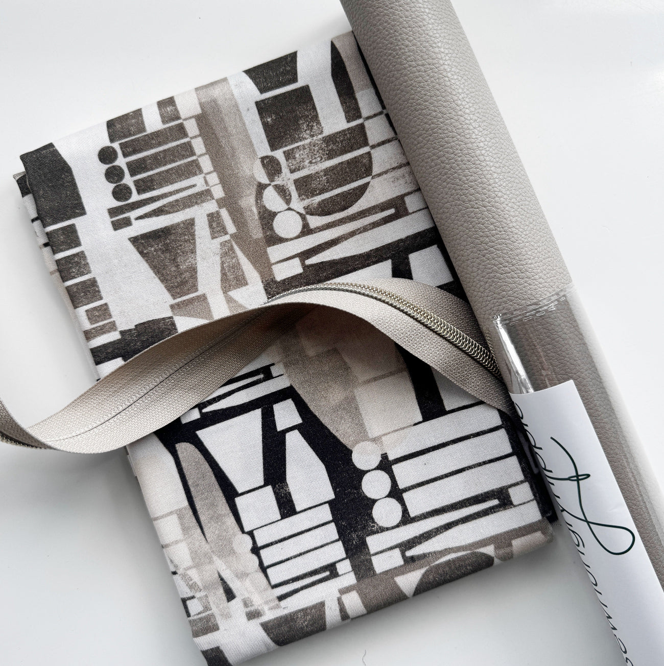 Stone gray faux leather paired with coordinating black and white modern abstract cotton fabric and silver #5 continuous zipper tape, perfect for handbags, backpacks, totes, wallets, and sewing projects.