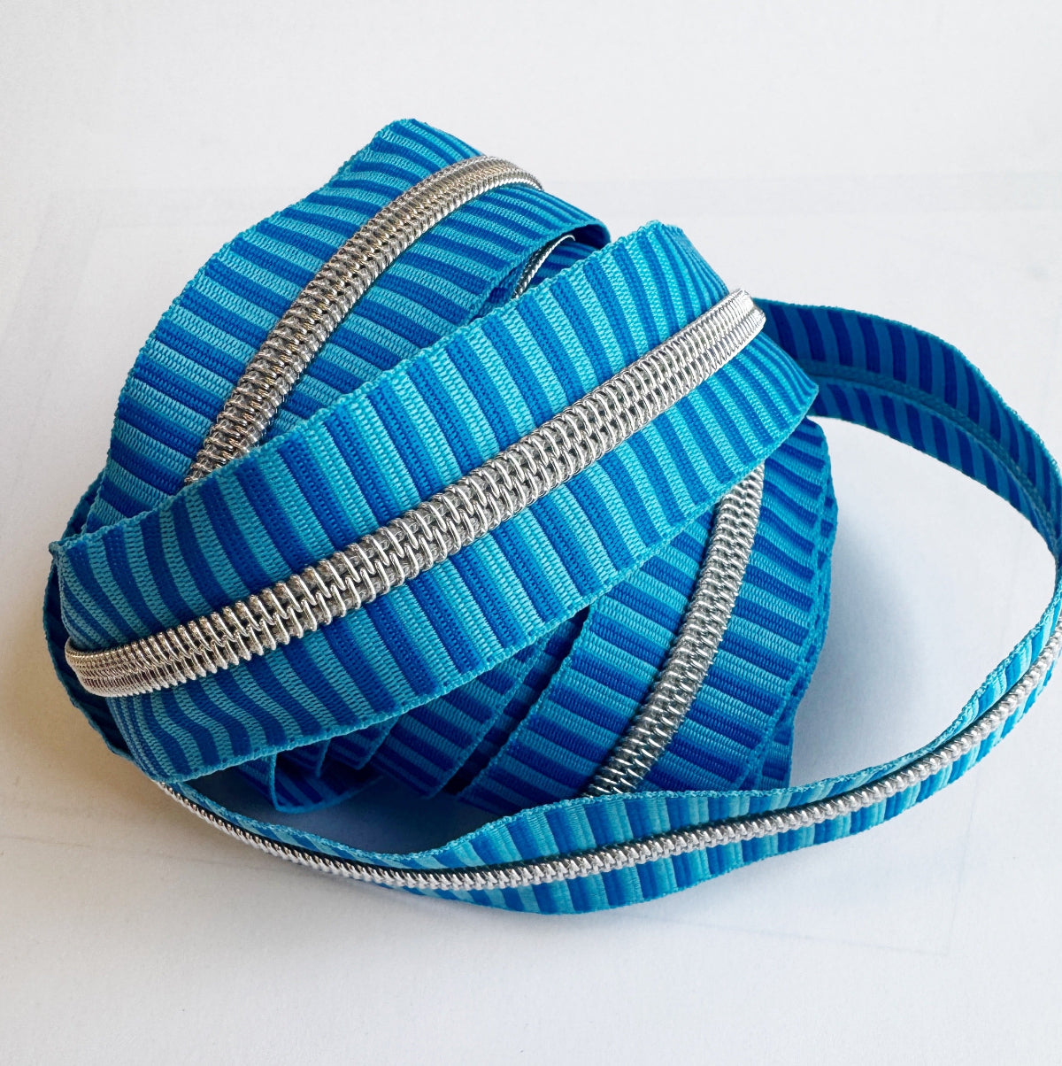Blue striped zipper with silver teeth on a white background