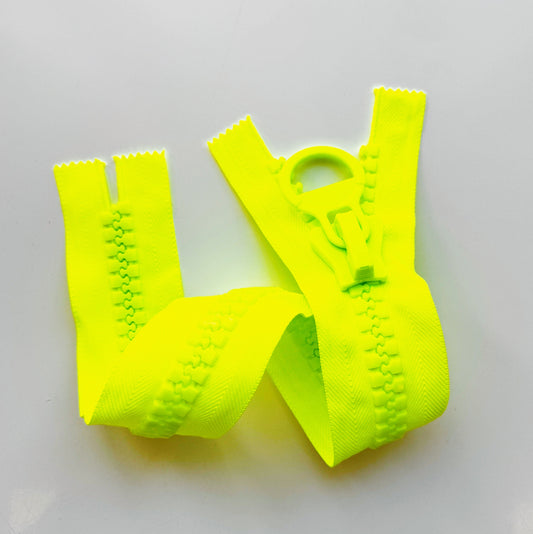 A bright neon yellow zipper tape, shown in multiple pieces folded together on a plain light gray background.